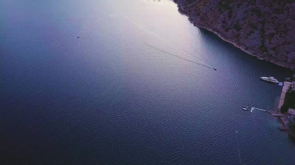 Kotor Körfezi Havalimanı. Beyaz motorlu tekne mavi sularda bir rıhtıma doğru ilerliyor.