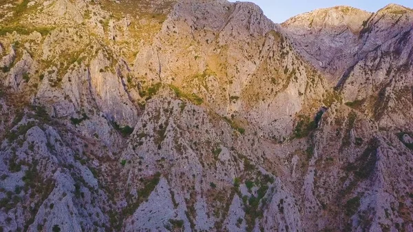 Gün batımında bir dağın kayalık yamaçlarında güneş ışığı ve gölgeler. Hava görüntüsü