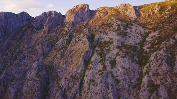 Gün batımında bir dağın kayalık yamaçlarında güneş ışığı ve gölgeler. Döndürme çekimi