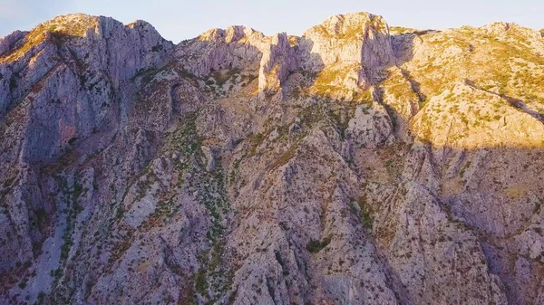 Kayalık tepenin üzerinden uçuyor. Gölgeler ve gün batımı kayalık bir yamaçta. Hava görüntüsü