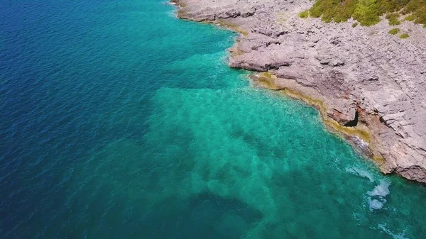 Kayalık kıyı şeridi ve turkuaz deniz havası. Deniz tabanı şeffaf suyla görülebilir.