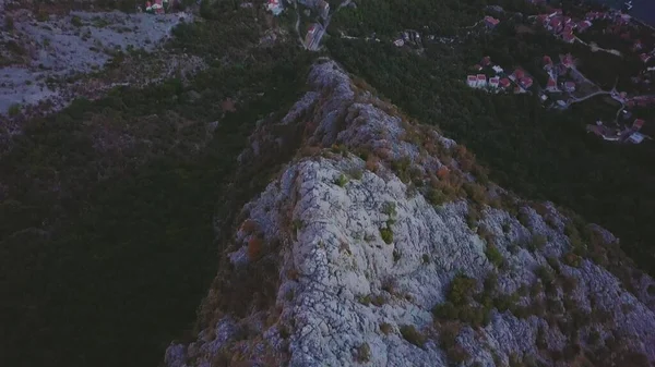 Kayalık tepe boyunca uçuyor. Karadağ 'ın Kotor Körfezi' ndeki bir dağın eteğindeki sahil köylerine gün batımı ışığı