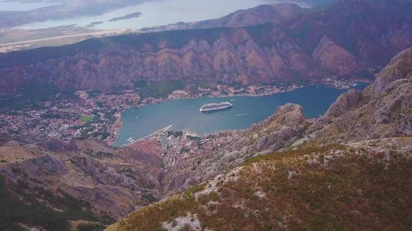 Dağlar arasında sahil kasabasını gören bir manzarayla tepenin üzerinden uçmak. Karadağ 'ın Kotor Körfezi Havalimanı