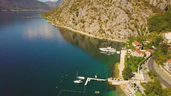 Demir atmış motorlu tekneleri olan küçük bir rıhtım. Dağlar arasındaki Kotor Körfezi 'nin havadan görüntüsü