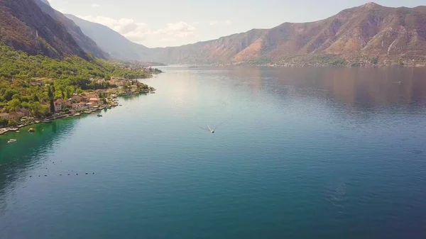 Deniz kıyısındaki deniz kenti havadan görünüyor. Sisli dağlar Kotor Körfezi 'nin suyunu yansıtıyor