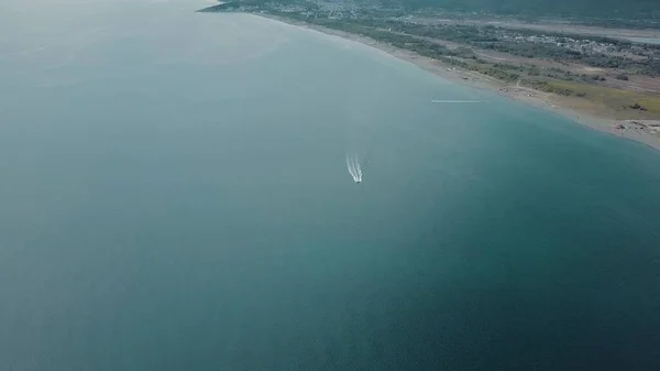 Sürat teknesi beyaz iz bırakarak mavi deniz sularında hareket ediyor. Adriyatik Denizi 'nin havadan görünüşü