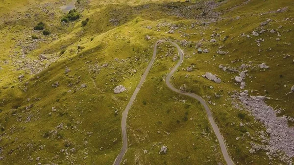 Araba Durmitor 'da kayaların ve taşların arasında virajlı yolda ilerliyor. Güneş ışığı geçidi havası