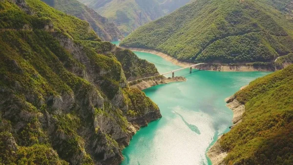 Koyu yeşil kanyonda, gök mavisi Piva Gölü 'nün üzerindeki köprü. Karadağ dağlarının havası