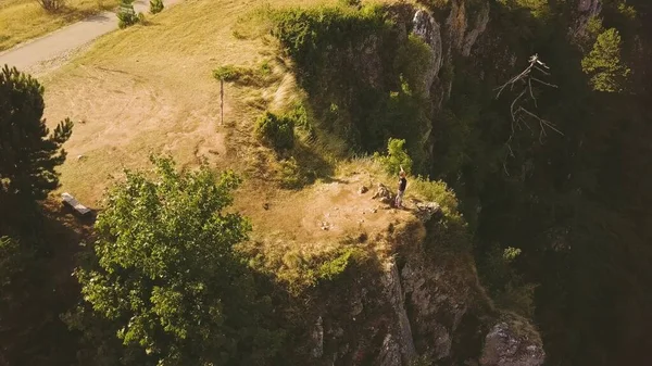 Kadın uçurumun kenarında elleri havada duruyor. Uçurum yüzeyinin havadan görüntüsü