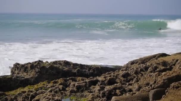 Surfista na onda azul do oceano com rochas — Vídeo de Stock