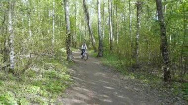 Kız ormanda bir patika üzerinde bir bisiklet sürmek