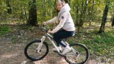 Kız ormanda bir patika üzerinde bir bisiklet sürmek