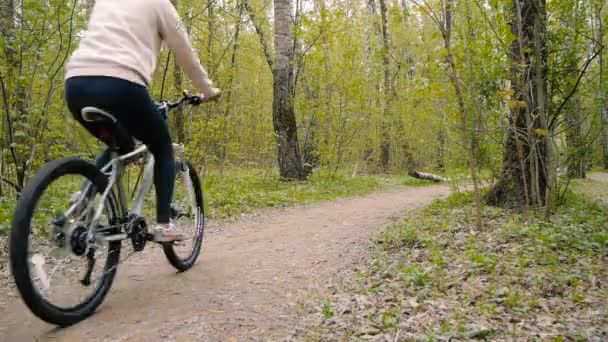 Chica monta una bicicleta en un sendero en el bosque — Vídeos de Stock