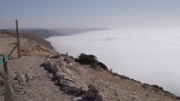 Молодая женщина смотрит на море из облаков в горах — стоковое видео