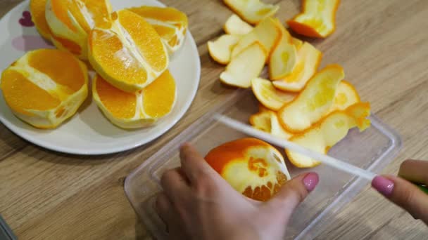 Snijden van verse sinaasappelen op een houten tafel — Stockvideo