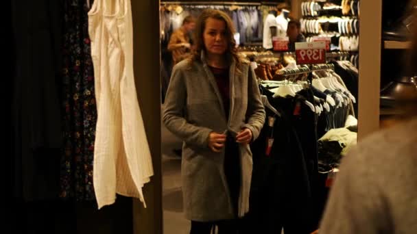 Mujer en la tienda de ropa ajuste en el vestido y mirando en el espejo — Vídeos de Stock