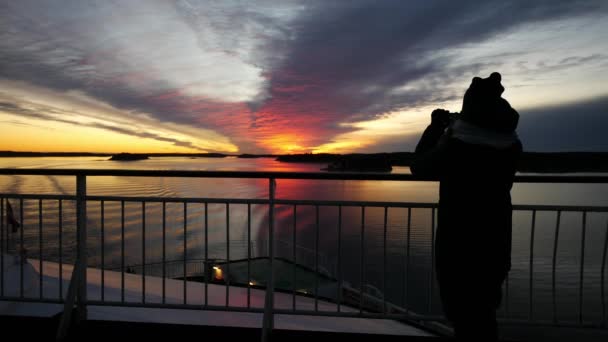 Cruzeiro mulher de férias do navio tirando foto com telefone inteligente desfrutando do pôr do sol em viagens no mar. Menina usando smartphone para tirar fotos do pôr do sol do oceano — Vídeo de Stock