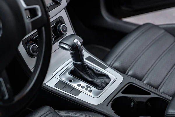 Siyah deri arabanın içini kapatın. Modern araba konseptinin detaylarını tasarlayın. Otomatik vites ve vites kolunun detaylarını yakın plan yapın. Araç içi - aygıtlar, sürüş konsepti