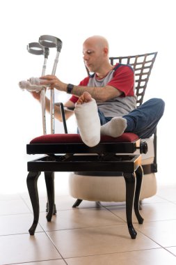 Kırık bir bilekle ve döküm bacak ile genç adam