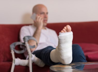 Young man with a broken ankle and a leg cast clipart