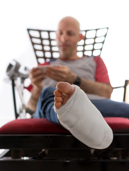 Young man with a broken ankle and a leg cast — Stock Photo, Image