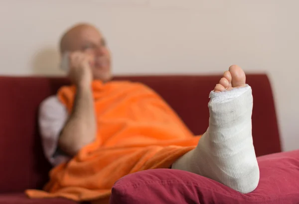 Young man with a broken ankle and a leg cast — Stock Photo, Image