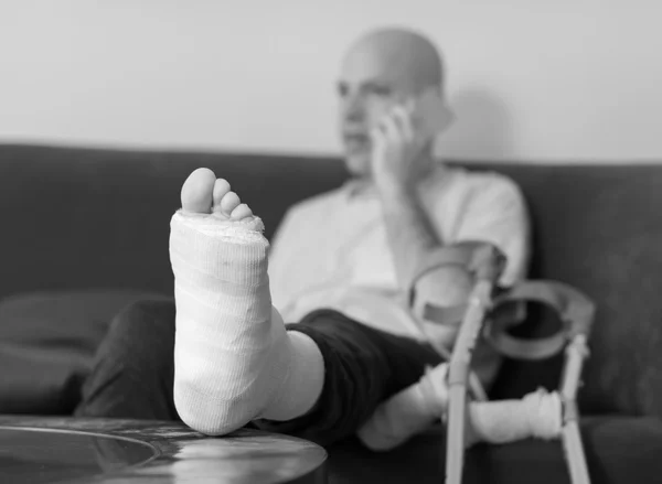 Junger Mann mit gebrochenem Knöchel und Gips — Stockfoto