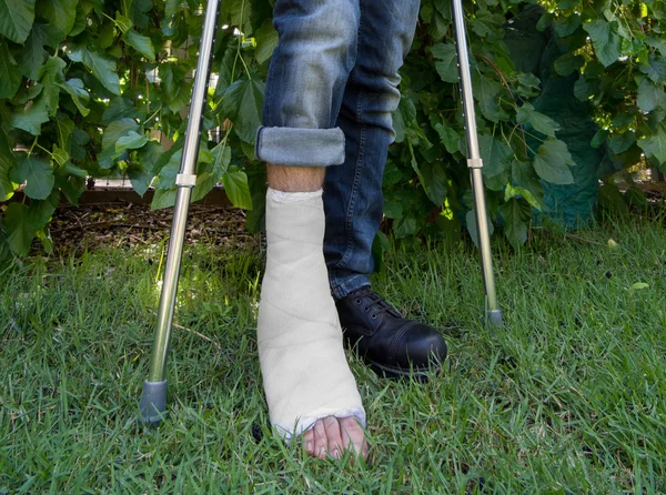 Jeune homme avec une jambe coulée dans un jardin — Photo