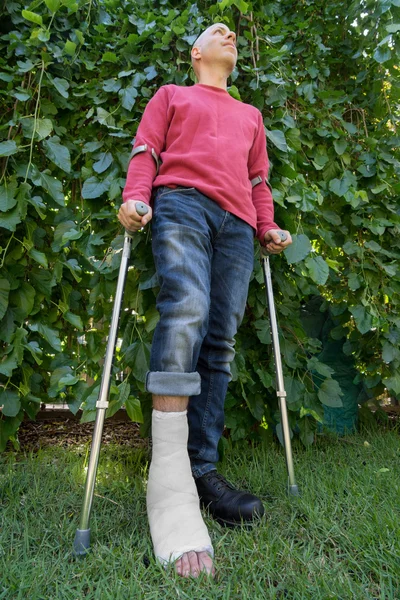 Joven con una pierna echada en un jardín — Foto de Stock