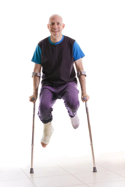 Kırık bir bilekle ve döküm bacak ile genç adam — Stok fotoğraf