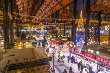 BuDAPEST - 30 Aralık 2019: Budapeşte 'deki renkli Büyük Pazar' ın tadını çıkaran insanlar, yeni yıl arifesi ve yeni dekorasyon arifesinde Noel için süslenmiş ve şenlikli