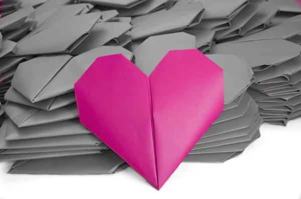 A red paper heart in a pile of grey ones for Valentine's Day — Stock Photo, Image
