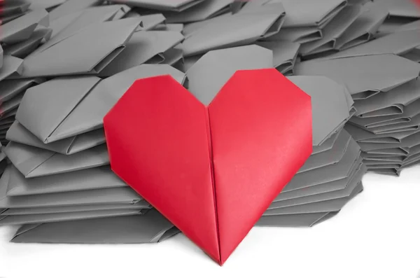 Un cuore di carta rosso in un mucchio di carta grigia per San Valentino — Foto Stock