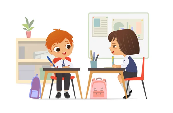 Cheerful elementary classmates wearing school uniform talking at lesson sitting at table with stationery vector flat illustration. Cute schoolboy and schoolgirl studying at primary classroom together — Stock Vector