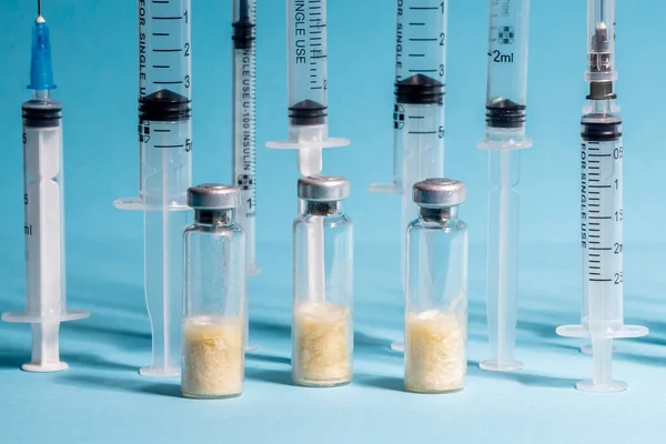 Three glass vials of vaccine, against the background of medical syringes. The concept of vaccination of the population against influenza and coronavirus. Selective focus, close-up, blue background — Stock Photo, Image