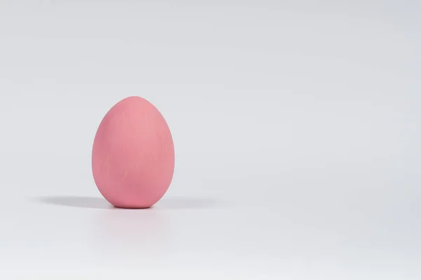 One vertical Easter egg, painted pink, is isolated on a white background with a soft shadow — Stock Photo, Image