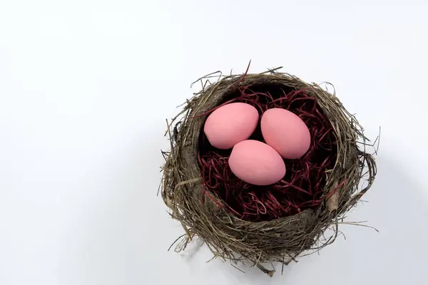 Barevná růžová velikonoční vajíčka izolovaná na bílém pozadí s hnízdem. Selektivní soustředění. Pohled shora. — Stock fotografie