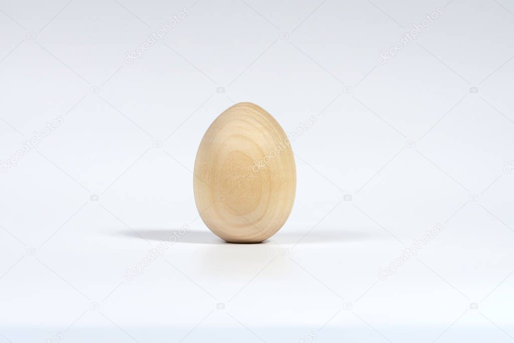 One vertical unpainted wooden egg isolated on a white background with a soft shadow. The Concept Of A Happy Easter