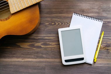 Online eğitim. Gitar reklamları için bir tasarım. Gitar, defter, tahta yüzeyde tablet. Üst görünüm, yakın çekim.