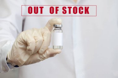 Plastik eldivenli ve beyaz önlüklü bir kadın doktorun elinde, arkaplandaki yazıya karşı bir ampul ilaç var: Stok dışı. Koronavirüse karşı aşı eksikliği, enfeksiyon....