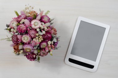 Bir buket çiçeğin ve boş ekranlı tabletin üst görüntüsü. Reklam için model: İnternet üzerinden çiçek siparişi