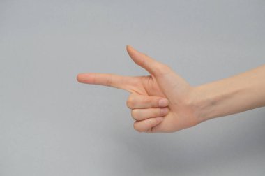 İşaret parmağıyla kadının eli işaret ediyor. Kırpma yolu ile yakın plan, gri izole arkaplan.