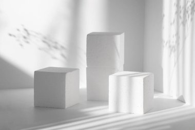 3D podyum, paketleme, kozmetik sunumları için. Üç beyaz kare sahne, farklı yüksekliklerde, çiçeklerin sert gölgesi olan temiz duvarların arka planına karşı. Güzellik konsepti.