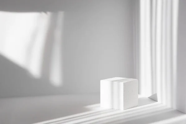 Paketleme ve kozmetik sunumları için 3D podyum. Pencerenin gölgesi olan temiz duvarların olduğu beyaz kare sahne.