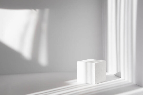 3-й подиум, для презентаций упаковки и косметики. Белая квадратная сцена на фоне чистых стен с тенью от окна.