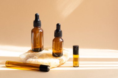 Kozmetik ürünleri için çeşitli kahverengi cam şişeleri, doğal ilaçlar, bej arka planda gerekli yağlar. Model Bırakan Şişe. Vücut bakımı ve kaplıca kavramı.