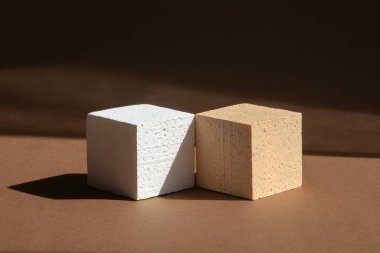 Kahverengi arka planda beyaz ve bej renkli iki boş tribün. 3D podyum, ürünlerin sunumu için, yüzeyde gölge bırakır. Güzellik endüstrisi kavramı