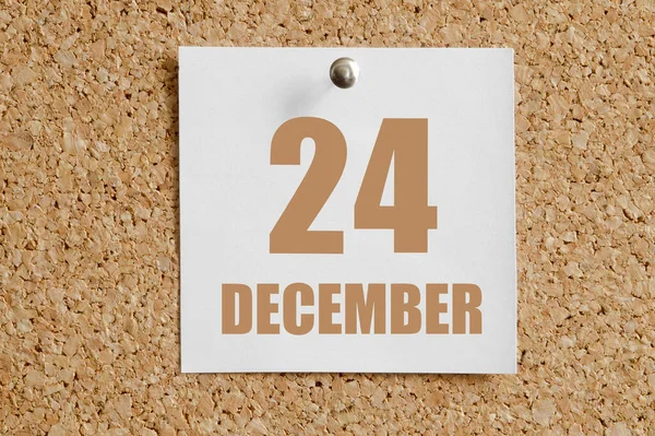 december 24. 24th day of the month, calendar date.White calendar sheet attached to brown cork board. Winter month, day of the year concept.