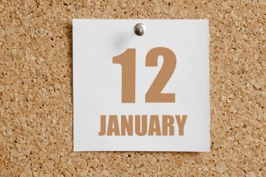 12 Ocak. Ayın 12. günü, takvim tarihi. Kahverengi mantar panoya takılı beyaz takvim kağıdı. Kış ayı, yılın günü konsepti..