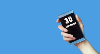 30 Eylül. Ayın 30. günü, takvim tarihi. Kadınlar cep telefonlarını mavi ekranlı, izole edilmiş arka planda tutarlar. Ayın son günü, yılın ilk günü.